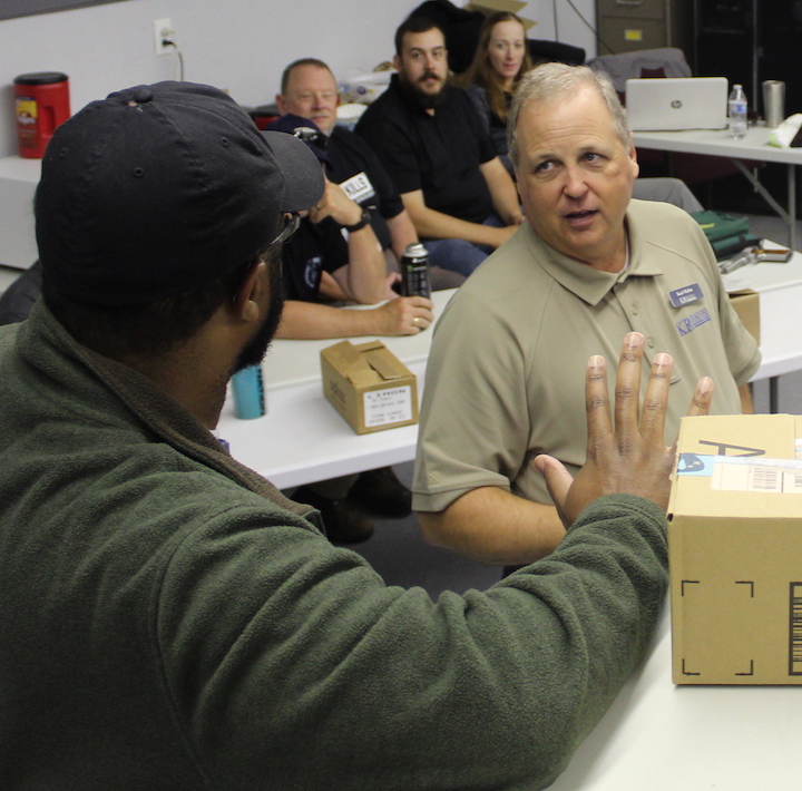 Rearranging classroom tables and using shipping boxes as props gives Karl Rehn the setting to act out a store scenario with a student while the rest of the class observes.
